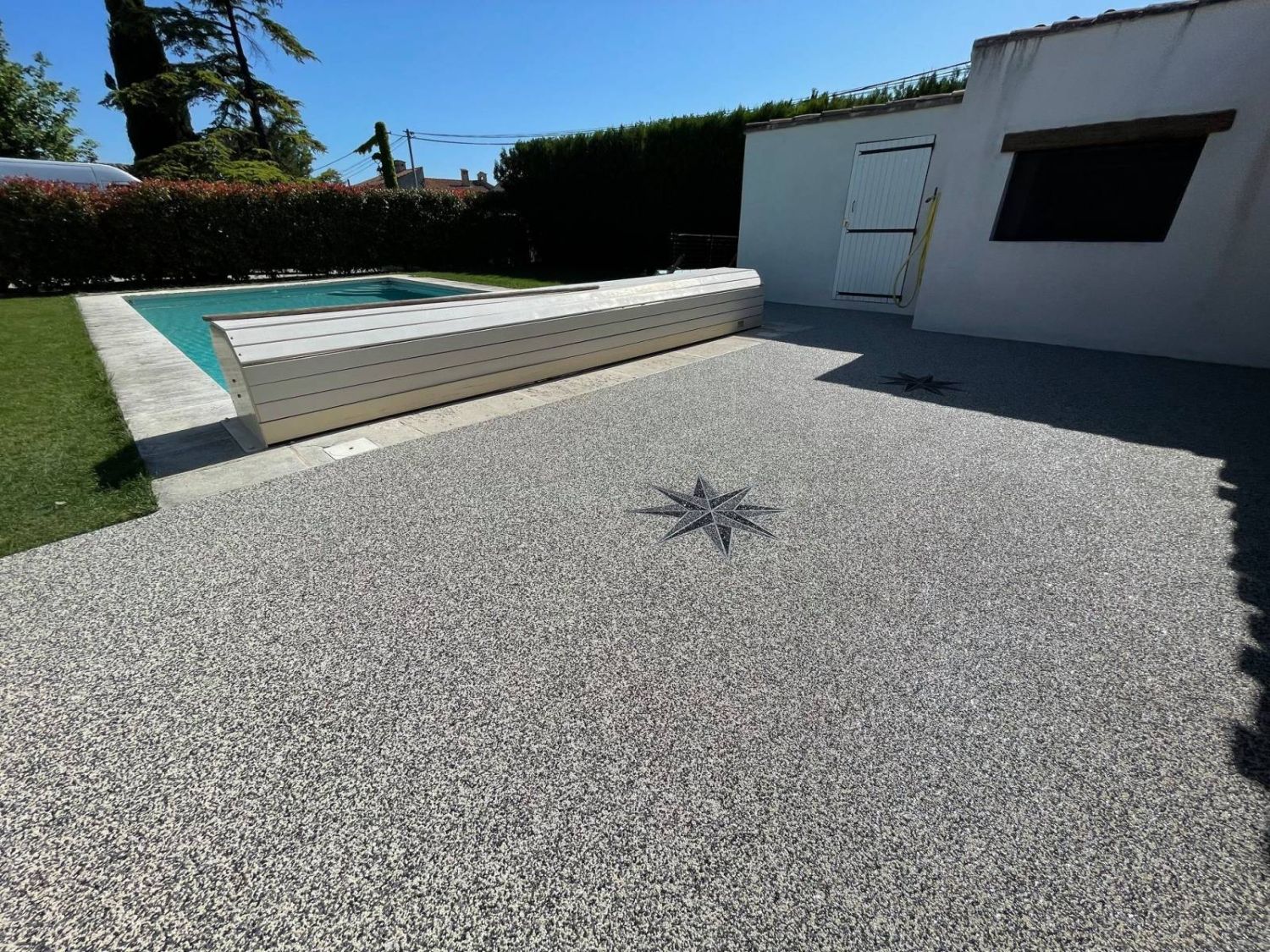 Terrasse piscine en résine gravier avec motif rose des vents